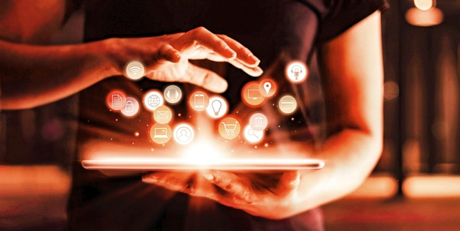 Hände halten ein Tablet, aus dem verschiedene, typische Internet-Themenbilder aufsteigen wie Warenkorb, Lupe, Weltkugel und so weiter